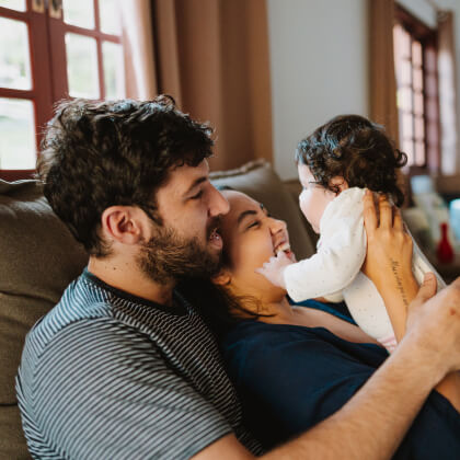 A young family with a newbord sitting on a couch
