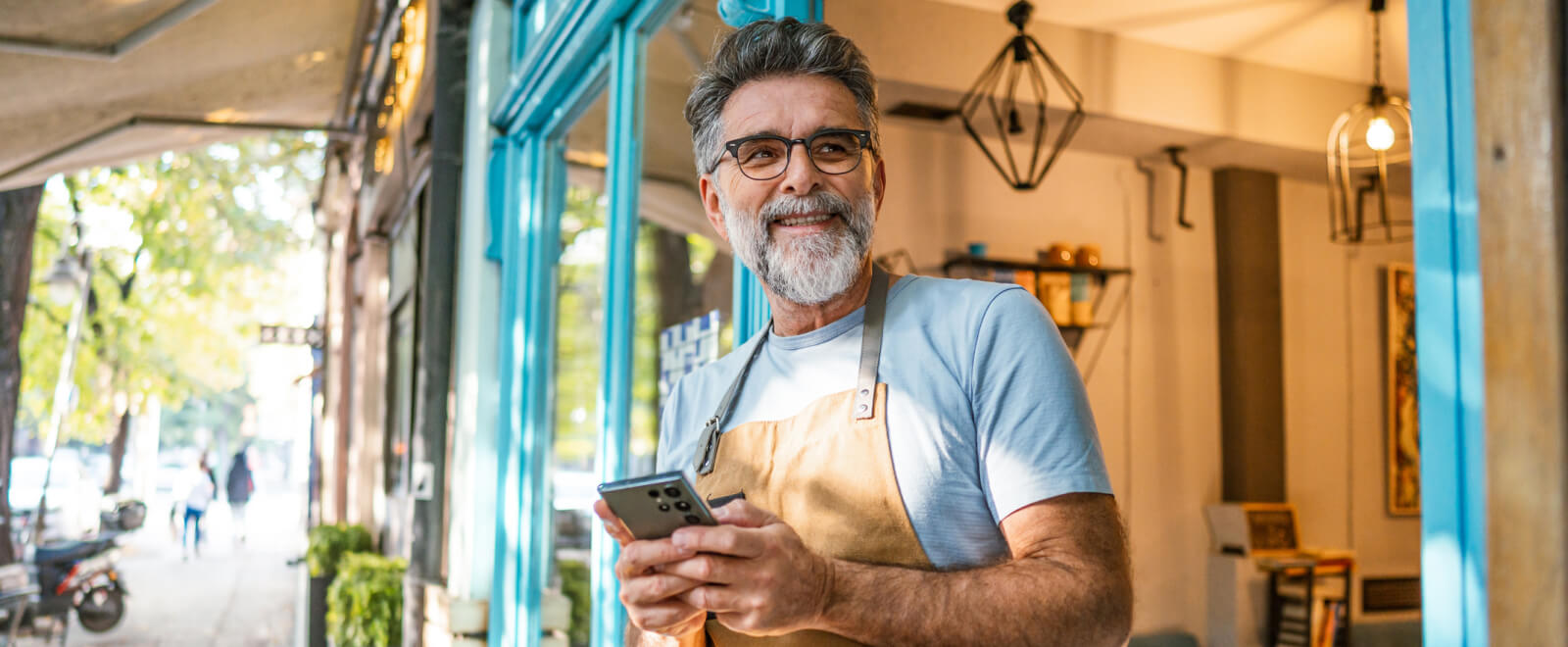 A man standing outside a shop and holding a smartphone