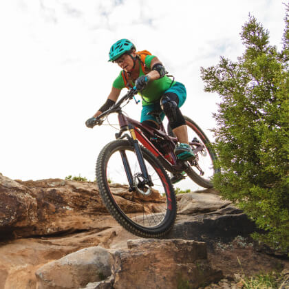 A woman riding a mountain bike down a steep boulder