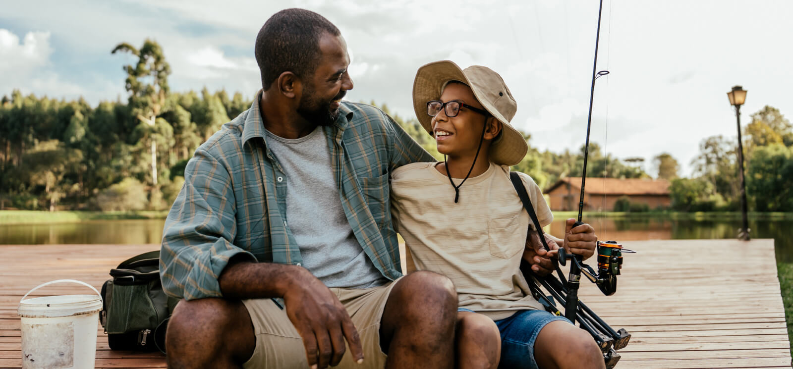 A dad and his kid fishing on a wooden dock