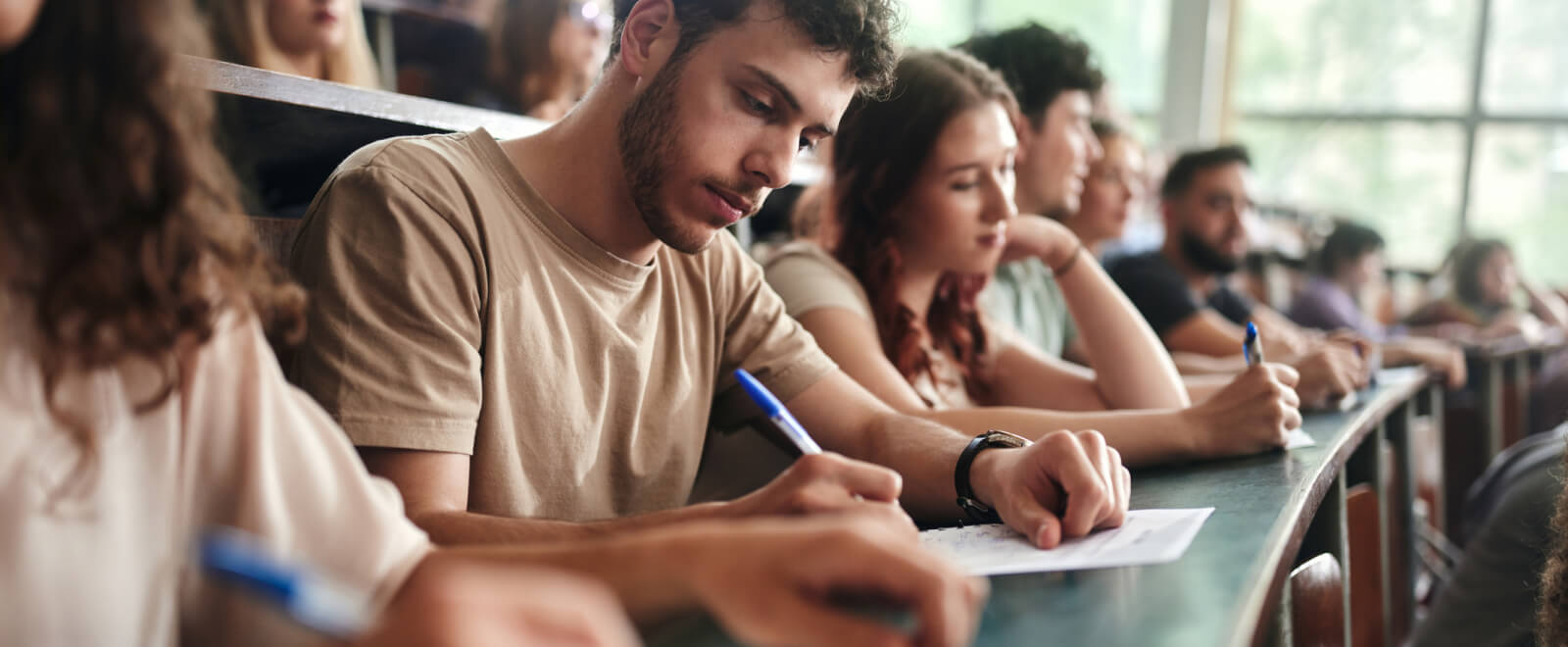 A group of college students taking notes in a classroom 