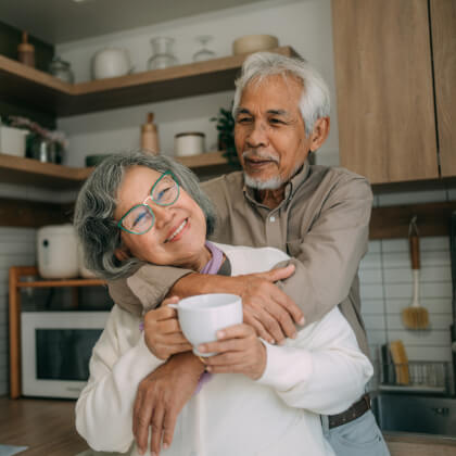 A mature couple embracing in a kitchen